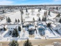 An aerial view of the property and its surrounding area, featuring a residential neighborhood with snow-covered homes and mature trees - 131 West Liberty Crescent, Millet, AB  - Outdoor With View 