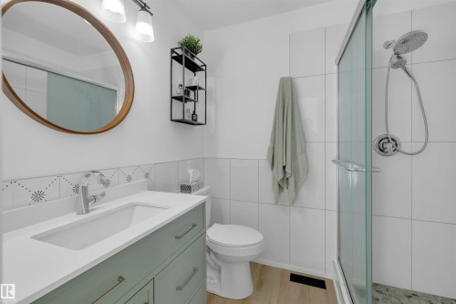 This bathroom features a vanity with a white countertop and a rectangular sink, a toilet, and a glass-enclosed shower with a handheld showerhead - 131 West Liberty Crescent, Millet, AB - Indoor Photo Showing Bathroom