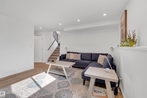 Living area featuring light wood flooring, recessed lighting, and a partial staircase with a wood handrail - 131 West Liberty Crescent, Millet, AB - Indoor Photo Showing Living Room