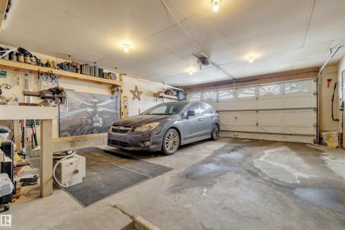 The property includes a garage with a roll-up door, exposed ceiling joists, and overhead lighting - 131 West Liberty Crescent, Millet, AB - Indoor Photo Showing Garage