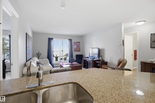 Living area featuring light gray walls, a window with blue curtains, and a view of the outdoors - 115 2208 44 Avenue, Edmonton, AB - Indoor