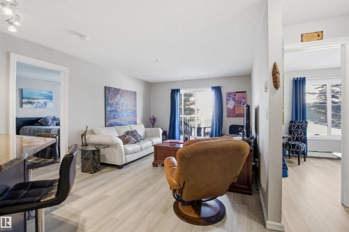 This bright and inviting living area features light-toned flooring, a light-colored sofa, and a balcony visible through a glass door - 115 2208 44 Avenue, Edmonton, AB - Indoor Photo Showing Living Room