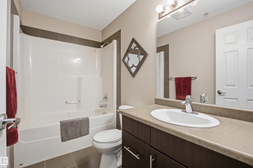 Bathroom featuring a combination shower and bathtub, a toilet, and a vanity with an integrated sink and mirror - 115 2208 44 Avenue, Edmonton, AB - Indoor Photo Showing Bathroom