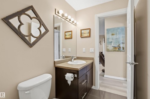 Well-appointed bathroom featuring a vanity with a white sink, a mirror with decorative framing, and a toilet - 115 2208 44 Avenue, Edmonton, AB - Indoor Photo Showing Bathroom