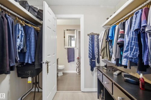 Walk-in closet featuring extensive hanging space, built-in shelving, and a vanity with drawers - 115 2208 44 Avenue, Edmonton, AB - Indoor With Storage