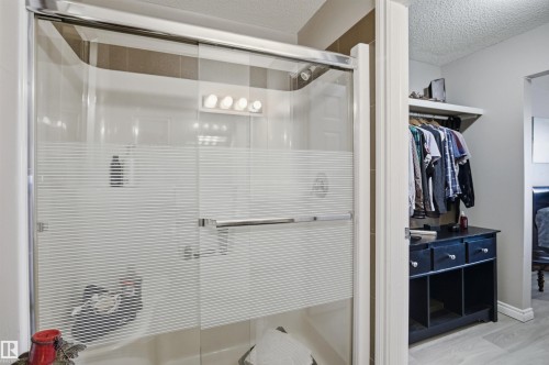 The property features a shower with sliding glass doors, a shower light fixture with four bulbs, and a built-in shower seat - 115 2208 44 Avenue, Edmonton, AB - Indoor Photo Showing Bathroom