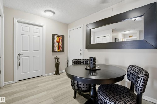 This inviting dining area features light-toned flooring, a round dark dining table, and upholstered dining chairs - 115 2208 44 Avenue, Edmonton, AB - Indoor Photo Showing Dining Room