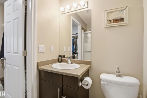 The bathroom features a vanity with a countertop and an integrated sink, illuminated by a light fixture above the mirror - 115 2208 44 Avenue, Edmonton, AB - Indoor Photo Showing Bathroom