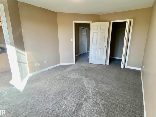 Unfurnished bedroom featuring light colored carpet and a spacious closet - 403 178 Bridgeport Boulevard, Leduc, AB - Indoor Photo Showing Other Room