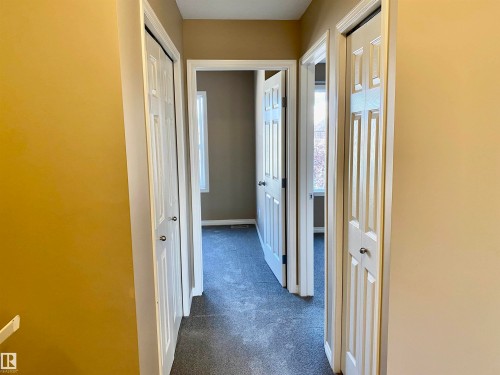Hall with dark colored carpet and baseboards - 403 178 Bridgeport Boulevard, Leduc, AB - Indoor Photo Showing Other Room
