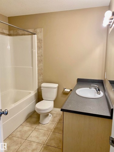 3rd bathroom - Full bath featuring vanity, a textured ceiling, light tile patterned floors, and bathtub / shower combination - 403 178 Bridgeport Boulevard, Leduc, AB - Indoor Photo Showing Bathroom