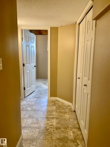 Hallway with a textured ceiling and baseboards - 403 178 Bridgeport Boulevard, Leduc, AB - Indoor Photo Showing Other Room
