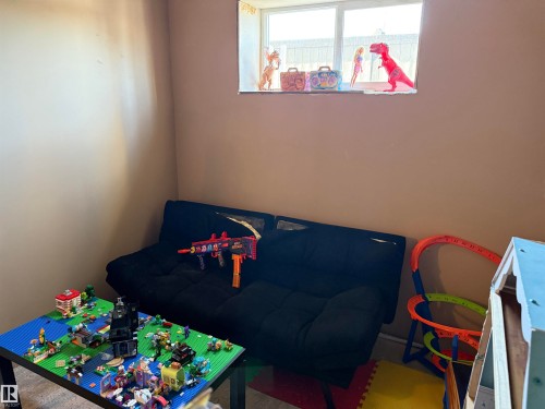 This room features a window providing natural light, warm-toned walls, and carpeted flooring - 403 178 Bridgeport Boulevard, Leduc, AB - Indoor