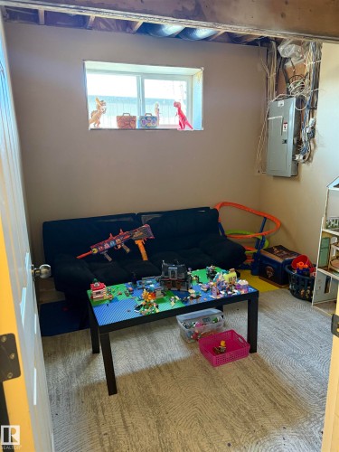 Finished basement room featuring a window providing natural light, a painted wall, and exposed ceiling joists - 403 178 Bridgeport Boulevard, Leduc, AB - Indoor Photo Showing Other Room