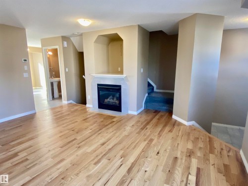 Unfurnished living room featuring a glass covered fireplace and light wood finished floors - 403 178 Bridgeport Boulevard, Leduc, AB - Indoor Photo Showing Other Room With Fireplace
