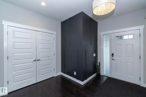 Entryway featuring dark hardwood flooring, a contemporary overhead light fixture, and a white front door with an adjacent frosted glass panel - 7608 179 Avenue, Edmonton, AB - Indoor Photo Showing Other Room