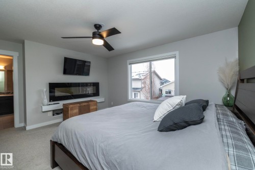 This space features a ceiling fan with integrated lighting, a wall-mounted fireplace, and a window providing natural light - 7608 179 Avenue, Edmonton, AB - Indoor Photo Showing Bedroom