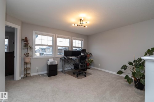 Spacious room featuring carpeted flooring, three windows with white frames, and a modern light fixture - 7608 179 Avenue, Edmonton, AB - Indoor Photo Showing Office