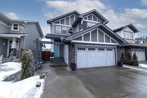 The property features a two-car garage with white doors and decorative windows, a light blue front door, and a stone facade on the lower level - 7608 179 Avenue, Edmonton, AB - Outdoor With Facade