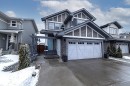 The property features a two-car garage with white doors and decorative windows, a light blue front door, and a stone facade on the lower level - 7608 179 Avenue, Edmonton, AB  - Outdoor With Facade 