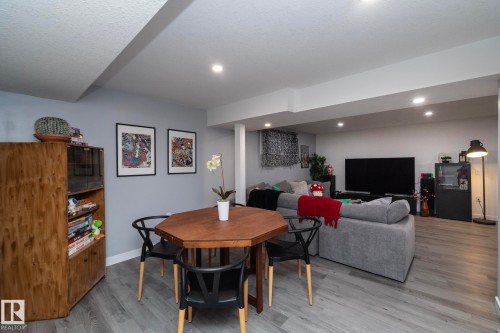 This open-concept living area features light grey walls, recessed ceiling lights, and grey wood-style flooring - 7608 179 Avenue, Edmonton, AB - Indoor
