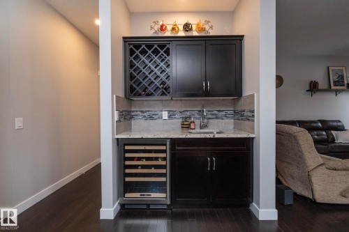 This property features a custom wet bar with dark cabinetry, a built-in wine rack, and a wine refrigerator - 7608 179 Avenue, Edmonton, AB - Indoor Photo Showing Other Room