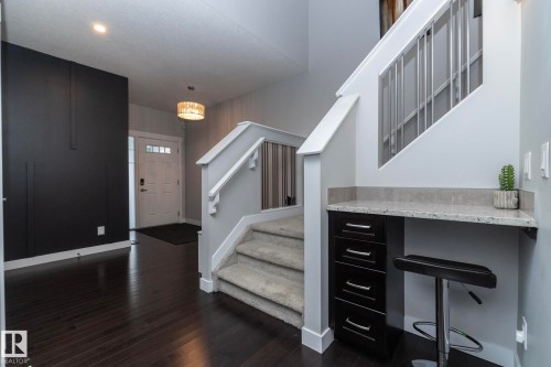 The entryway features dark wood flooring, a white front door with glass panels, and a decorative light fixture - 7608 179 Avenue, Edmonton, AB - Indoor Photo Showing Other Room