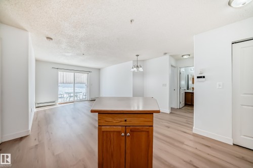 This property features light-colored flooring, white walls, and a sliding glass door providing access to an exterior space - 126 16221 95 Street, Edmonton, AB - Indoor Photo Showing Kitchen