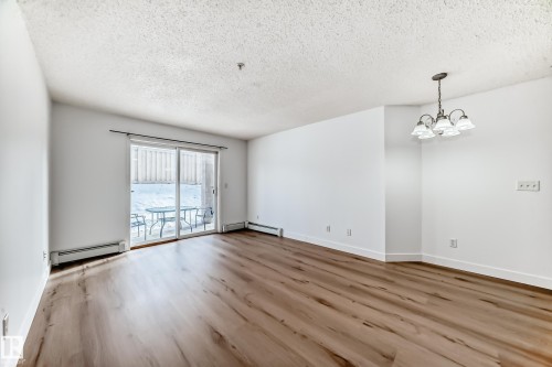 Living space featuring hardwood flooring, white walls, and a glass sliding door leading to an outdoor area - 126 16221 95 Street, Edmonton, AB - Indoor Photo Showing Other Room