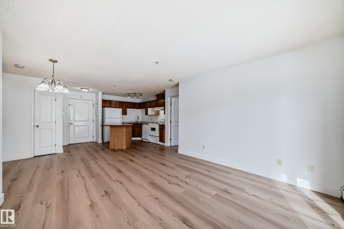 Open concept living space featuring wide plank flooring and a kitchen with wooden cabinetry and white appliances - 126 16221 95 Street, Edmonton, AB - Indoor