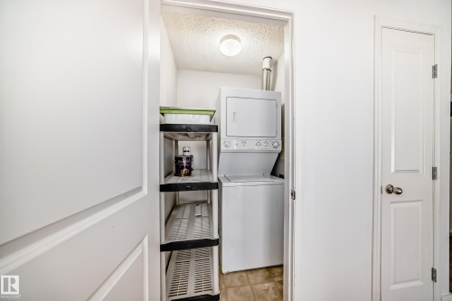 Dedicated laundry area featuring a stackable washer and dryer unit, tiled flooring, and a ceiling-mounted light fixture - 126 16221 95 Street, Edmonton, AB - Indoor Photo Showing Laundry Room