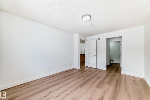 The property features light wood-look flooring throughout, complemented by white walls and trim - 126 16221 95 Street, Edmonton, AB - Indoor Photo Showing Other Room
