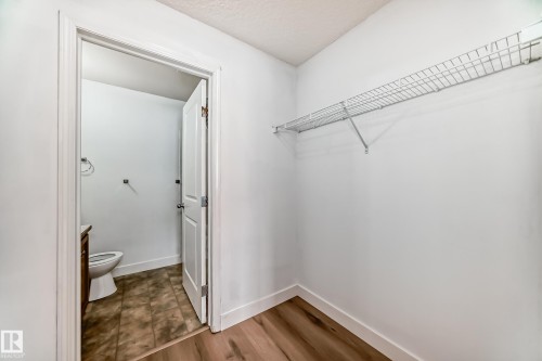This area features light wood-style flooring and a wire shelving unit - 126 16221 95 Street, Edmonton, AB - Indoor
