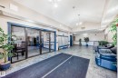 The building features a spacious common area with tiled flooring, vaulted ceilings, and a seating area with blue leather sofas - 126 16221 95 Street, Edmonton, AB  - Indoor Photo Showing Other Room 