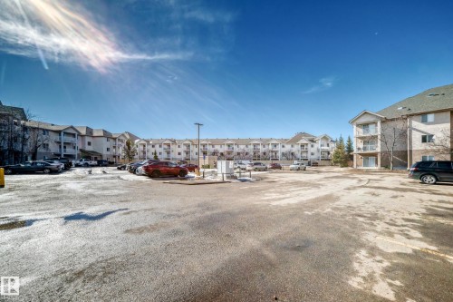 The property features a large parking area with apartment buildings in the background - 126 16221 95 Street, Edmonton, AB - Outdoor