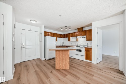 The property features a kitchen with wood cabinetry, white appliances, and a wood island - 126 16221 95 Street, Edmonton, AB - Indoor Photo Showing Kitchen