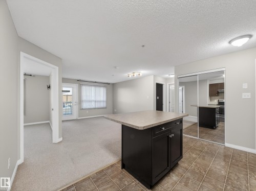 The property features a kitchen with dark cabinetry, a range, and a refrigerator, complemented by tile flooring - 1111 9363 Simpson Drive, Edmonton, AB - Indoor Photo Showing Other Room