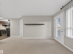The open concept living area features light-colored carpeting and neutral painted walls - 