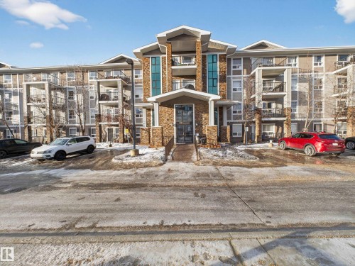 The property features an exterior with a stone facade entrance, balconies, and a paved parking area - 1111 9363 Simpson Drive, Edmonton, AB - Outdoor With Facade