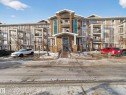 The property features an exterior with a stone facade entrance, balconies, and a paved parking area - 1111 9363 Simpson Drive, Edmonton, AB  - Outdoor With Facade 