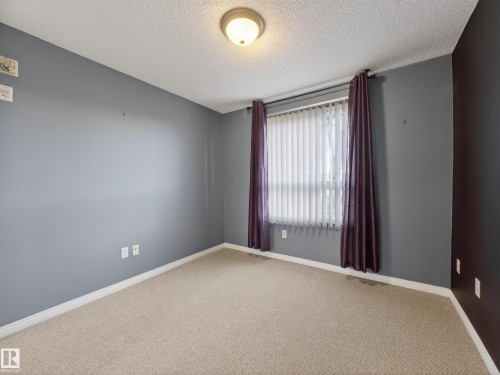 This room features light-colored carpeting, a window with vertical blinds, and a ceiling light fixture - 1111 9363 Simpson Drive, Edmonton, AB - Indoor Photo Showing Other Room