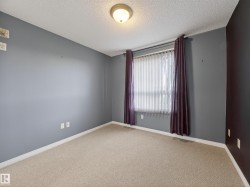 This room features light-colored carpeting, a window with vertical blinds, and a ceiling light fixture - 
