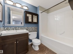 The bathroom features a vanity with a white sink, a decorative mirror, and a medicine cabinet - 