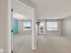 This interior view features light-colored carpeting, neutral painted walls, and a room with a vibrant accent wall - 