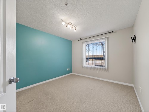 This room features a window with vertical blinds, a ceiling-mounted light fixture, and carpet flooring - 1111 9363 Simpson Drive, Edmonton, AB - Indoor Photo Showing Other Room