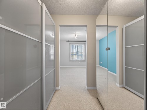 The property features carpeted flooring throughout, with a mirrored closet door and frosted glass closet doors - 1111 9363 Simpson Drive, Edmonton, AB - Indoor Photo Showing Other Room