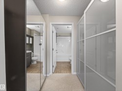 Hallway with carpeted flooring, featuring a mirrored closet door and a second closet with frosted glass panels - 