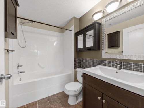 Bathroom featuring a white tub and shower combination, a dark wood vanity with a white sink, and a tiled floor - 1111 9363 Simpson Drive, Edmonton, AB - Indoor Photo Showing Bathroom