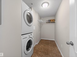 Laundry area featuring a stacked washer and dryer, tile flooring, and a wall-mounted shelf - 