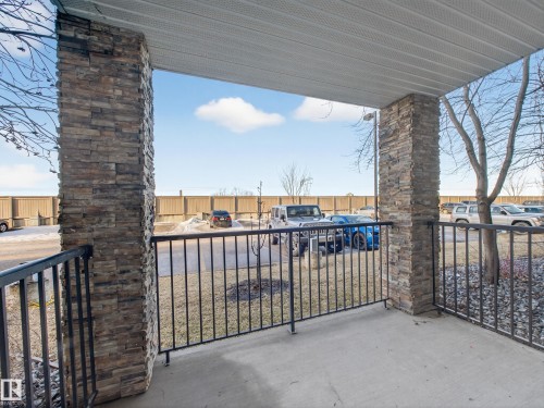 The property features a patio with concrete flooring, stone veneer columns, and a black metal railing - 1111 9363 Simpson Drive, Edmonton, AB - Outdoor